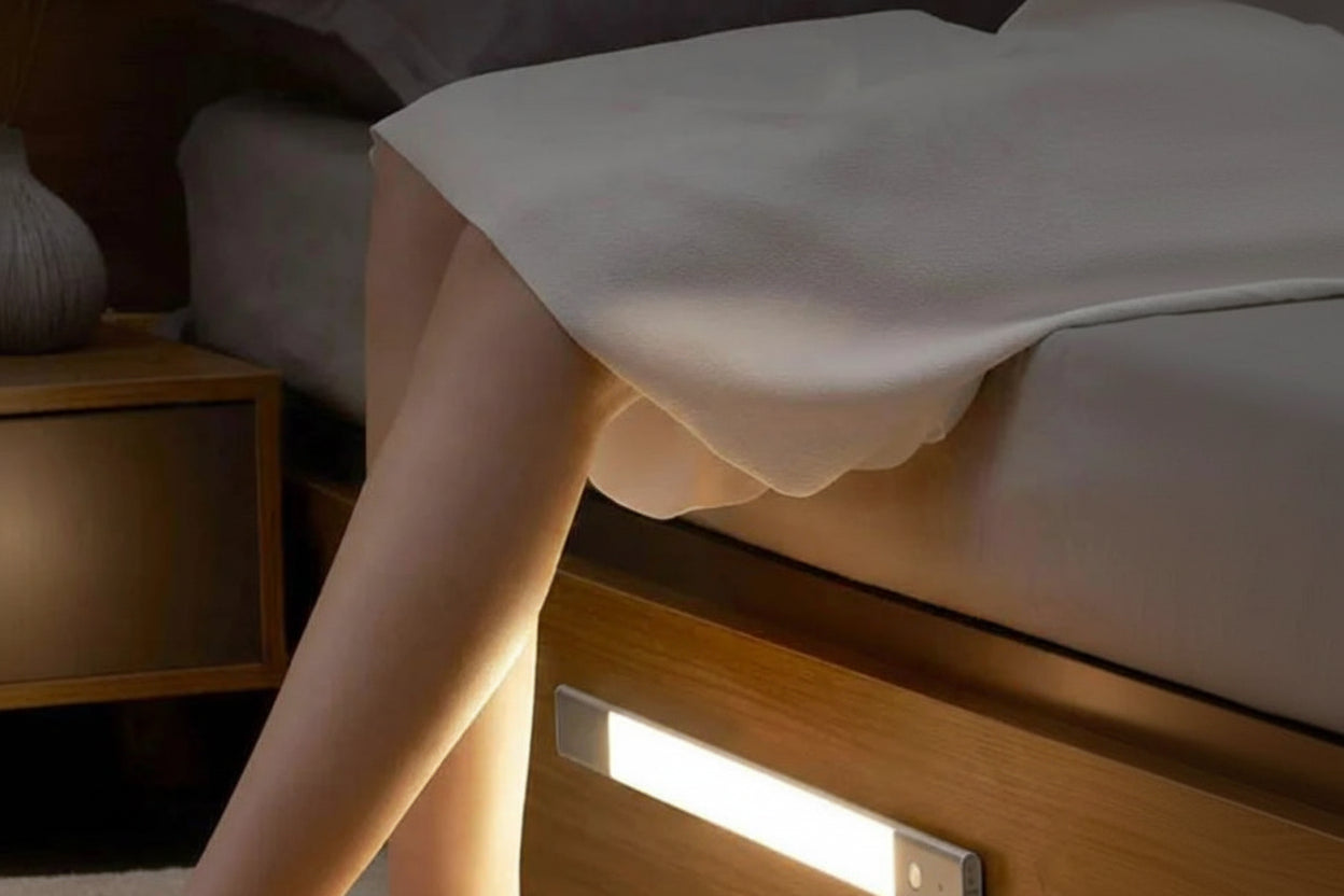 Person using a LED strip light under a bed for illumination